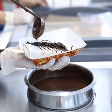 Staff drizzling chocolate over a paleta in a Paleta Bar tray