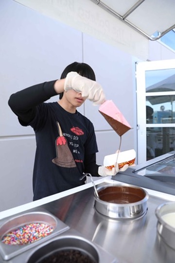 Team member dipping a strawberry paleta in chocolate at the Paleta Bar cart
